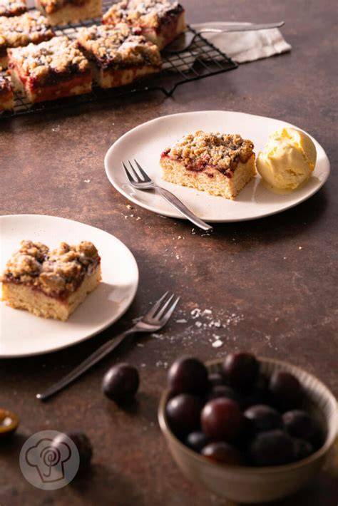 Serviervorschlag: Zwetschgenkuchen-Stücke auf Teller mit Sahnehaube und frischer Minze