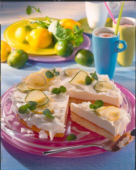 Sommerliche Zitronen-Limetten-Torte auf rustikalem Tisch mit Limetten, Zitronen und Minze