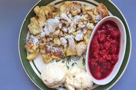 Soufflé auf Teller, begleitet von Kugel Vanilleeis und Himbeeren
