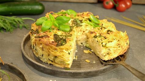 Spaghetti Torte angeschnitten auf rustikalem Holztisch, mit Beilagen