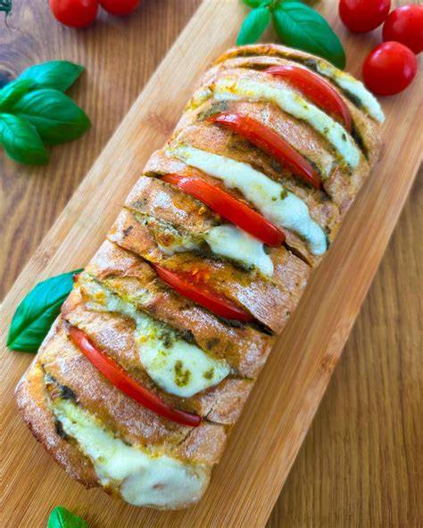 Spinat-Biskuitrolle aufgeschnitten, Füllung aus Frischkäse und Mozzarella, serviert auf Holzbrett