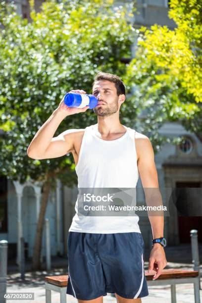 Sportler trinken Apfelschorle aus Flasche