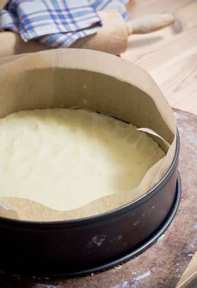 Springform mit Käsekuchen, mit eingefettetem Rand und Backpapier
