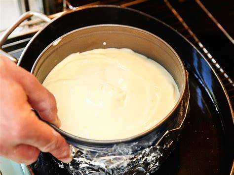 Springform mit New York Cheesecake im Wasserbad im Ofen