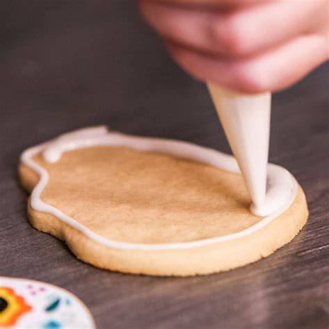 Spritzbeutel mit Royal Icing beim Verzieren von Keksen