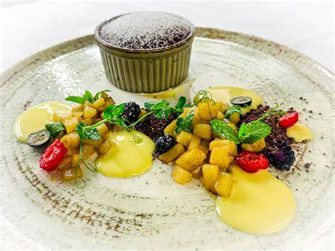 Stück Apfel-Mango-Torte auf einem modernen Dessertteller, daneben frische Früchte als Deko