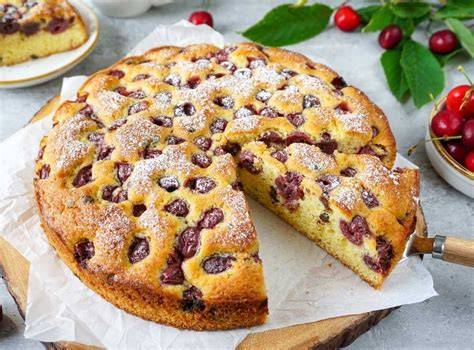 Stück Kirschkuchen mit Joghurt auf Teller, sommerlich dekoriert