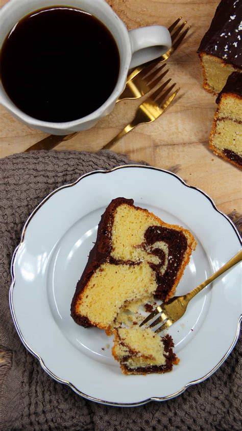 Stück Marmorkuchen neben Tasse Kaffee auf gestärkter Tischdecke