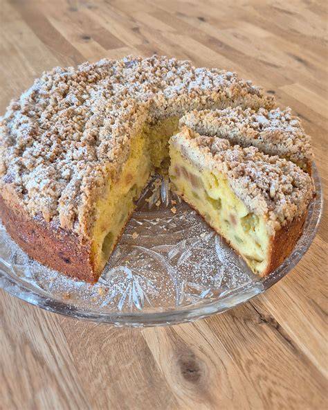Stück Rhabarber Streuseltarte mit Sahne auf einer Tortenplatte