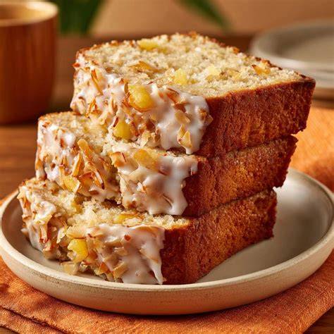 Stück saftiger Ananas-Rührkuchen auf einem Teller, daneben frische Ananas