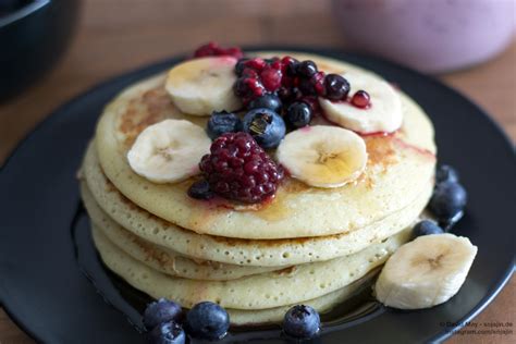 Stapelhügel kleiner Pancakes mit Beeren und Banane