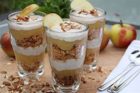 Stimmungsvolle Dessert-Szene mit Äpfeln, Zimtstangen und Gläsern mit Schichtdessert