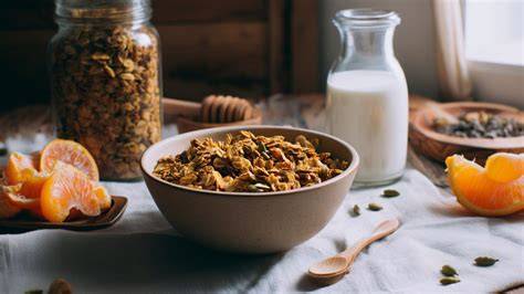 Stimmungsvolle Frühstücksszene mit Schüssel Lebkuchen-Granola, Kaffee und Orangen