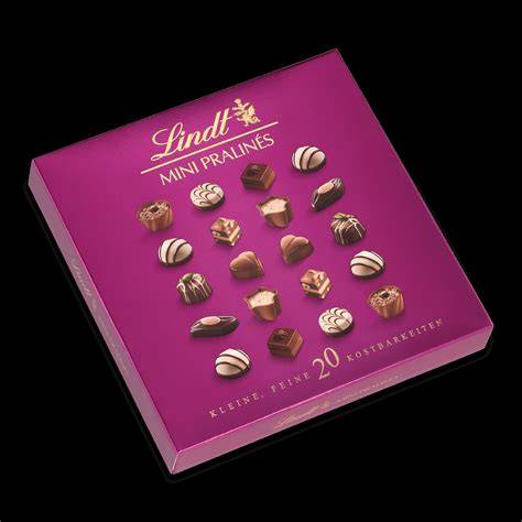 Stimmungsvolle Weihnachtsstillleben mit Lindt Mini Pralinés, Tannenzweigen und Kerzen