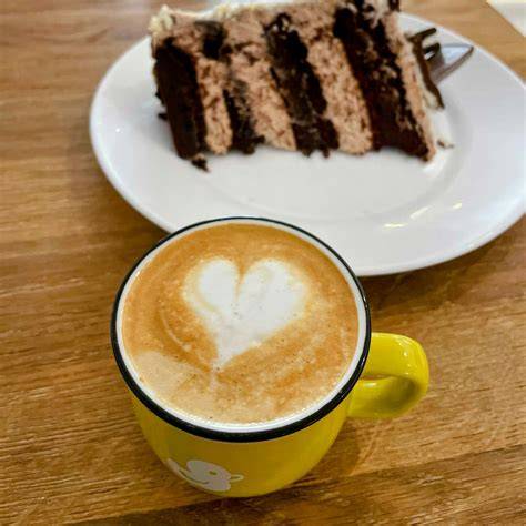 Stimmungsvolles Bild: Ein Stück Apfel-Mohn-Quark-Kuchen und Tasse Cappuccino am Fenster