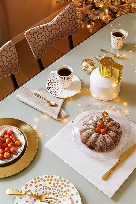 Stollenkuchenstücke auf weihnachtlich gedecktem Tisch, Tasse Kaffee und Geschenkbox