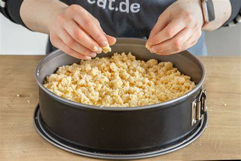 Streusel auf Aprikosenkuchen verteilen