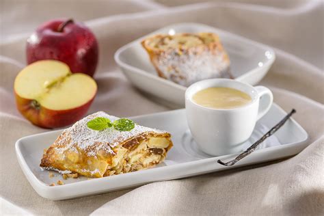 Strudelstücke auf Teller mit Vanillesoße und Kaffee