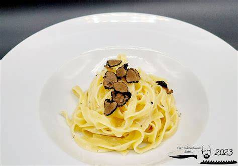 Tagliatelle mit Trüffel und Lachs, angerichtet mit Parmesan und frischem Trüffel