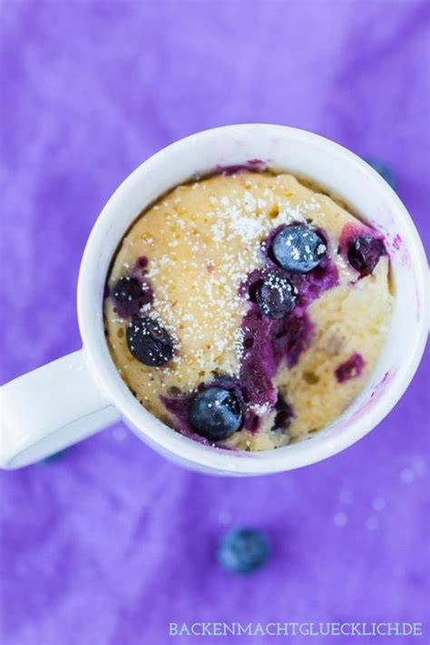 Tasse mit frisch gebackenem Mug Cake und frischen Blaubeeren
