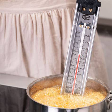 Thermometer über einem kochenden Topf mit Bonbonmasse