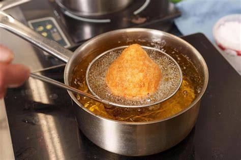 Thermometer und Holzlöffel: Öltemperatur prüfen