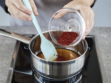 Topf mit Honig und Chilischoten beim Erwärmen