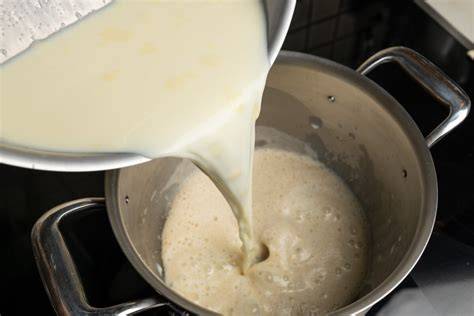 Topf mit köchelnder Milch zur Kondensmilch-Herstellung