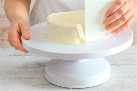 Torte auf Drehplatte beim Glätten mit Teigkarte