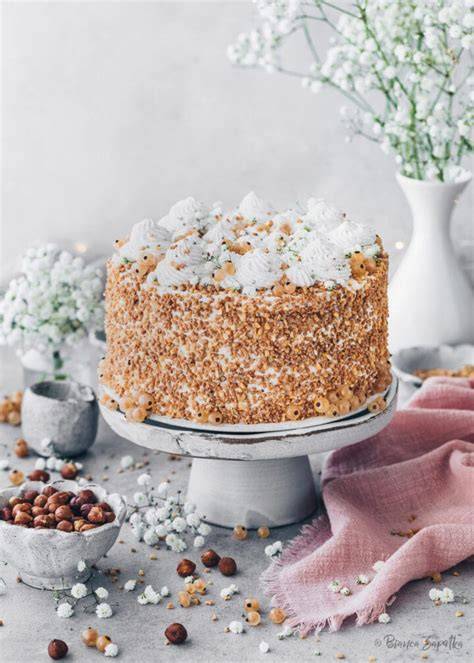 Torte dekoriert mit Nougattuffs, Waffelröllchen und gehackten Haselnüssen