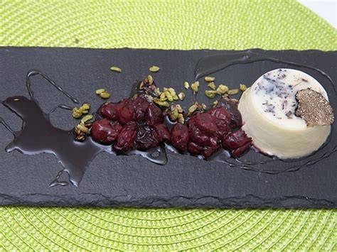 Trüffel Panna Cotta mit Kirschkompott und Crunch, serviert auf einem eleganten Teller