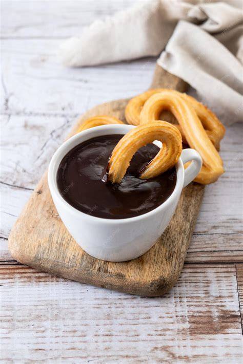 Traditionelle spanische Churros mit Schokosauce auf einem Holztisch