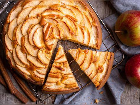 Traditioneller Apfelkuchen auf Holzbrett und Äpfel daneben