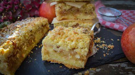 Unterschiedliche Apfelsorten für Apfel Streuselkuchen auf einem Holztisch mit Zutaten