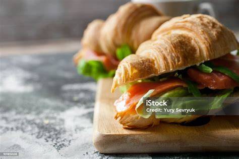 Vegan gebackene Croissants auf Holztisch; Zutaten (Mehl, Margarine, Pflanzendrink, Hefe) nebeneinander