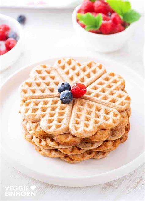 Vegane, gesunde Waffeln angerichtet auf einem Teller, daneben Apfelmus und frische Früchte