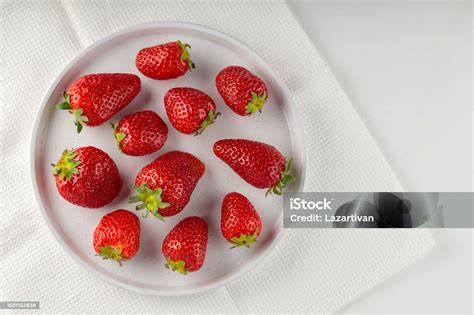Vegane Käsekuchen-Variante auf weißem Teller, frische Erdbeeren als Deko