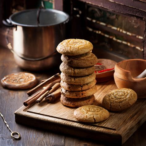 Vegane Plätzchen auf einem rustikalen Holzbrett, verschiedene Ausstecher und Zutaten rundherum