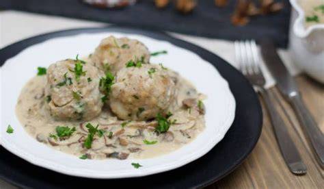 Vegane Semmelknödel mit Pilzrahmsoße und frischer Petersilie angerichtet