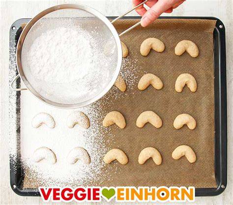 Vegane Zimtplätzchen auf Backpapier nach dem Backen, mit Puderzucker bestreut