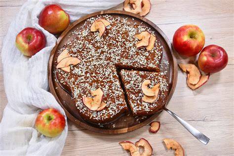 Veganer Apfel-Kokos-Kuchen angerichtet mit Äpfeln und gerösteten Kokoschips