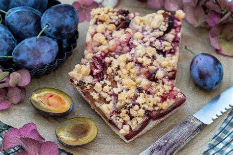 Veganer Zwetschgenkuchen vom Blech mit Zimtstreuseln auf rustikalem Holzbrett