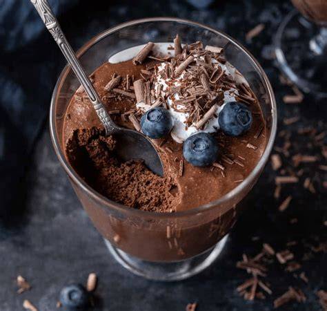 Veganes Dessert im Glas mit Kakaopulver bestäubt und Früchten garniert