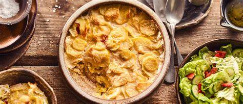 Veganes Kartoffelgratin serviert mit grünem Salat und Kräutern