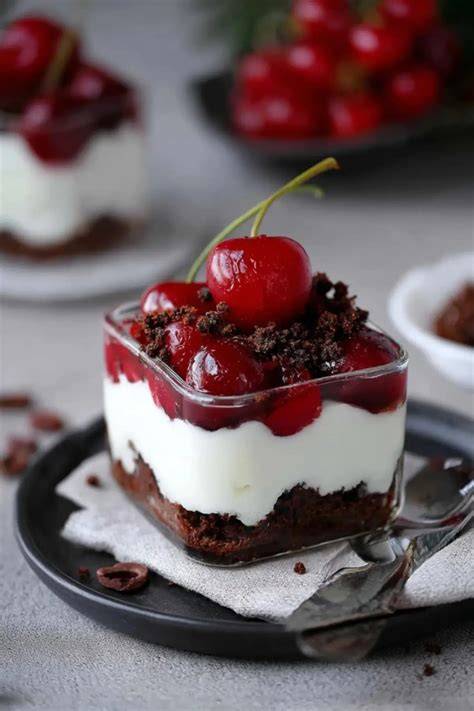 Verschiedene Cremeschichten mit Quark und Kirschen im Glas