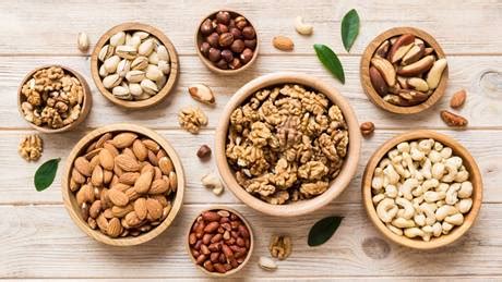 Verschiedene Dekorationen: Nüsse, Mandeln, Smarties, Zuckerperlen in kleinen Schälchen