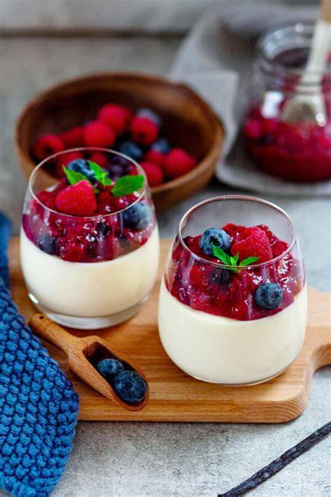 Verschiedene Dessertgläser mit Panna Cotta, Beeren und Sahnehäubchen