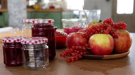 Verschiedene Gläser mit Apfelmarmelade und gemischten Früchten auf einem Küchentisch