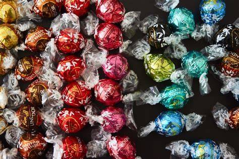 Verschiedene Lindt Lindor Kugelsorten arrangiert auf einem Teller mit Nahaufnahme der Füllung