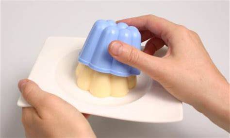 Verschiedene Puddingförmchen und Pudding vor dem Stürzen